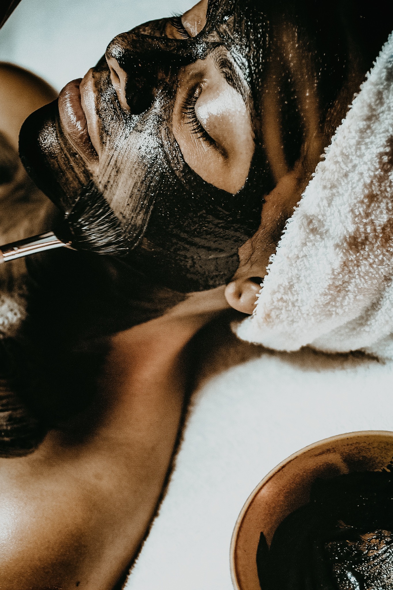 Aplicación de una mascarilla facial oscura con una brocha
